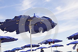 View of blue-wind-driven sea umbrellas with sky photo