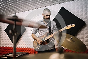 View through blurred cymbals of rock musician playing electric guitar