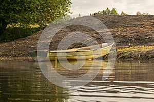 View of the boat on the shore of the lake, reflections in the calm water of the lake, summer