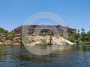 A view from a boat on a three-story building with a brown facade on the shore of Lake Nasser in Egypt. Architecturally nice