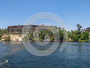 A view from a boat on a three-story building with a brown facade on the shore of Lake Nasser in Egypt. Architecturally nice