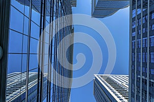 View from the bottom of modern glass buildings with blue sky background