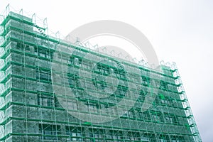 A view from the bottom of an office building being renovated with green slans