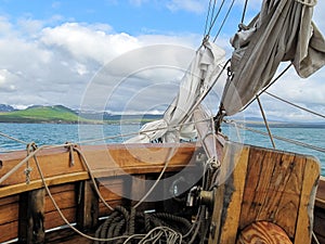 View from the bow of an old sailboat sailing in the Arctic sea with land in the background photo