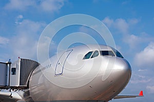 View of the bow of a passenger plane and the cockpit with a wing at the gangway