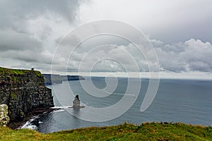 View of the Branaunmore sea stack and a boat sailing in the ocean in the Cliffs of Moher