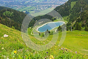 View from Brauneck mountain over flower meadow to artificial lake and Isar valley