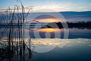 View of a bridge connecting the coasts and reflecting on the river at sunset