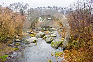 View from the bridge on a small river that flows through the boulders and the granite stone canyon in the background on the hills