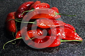 BRIGHT RED CHILIS ON A POLISHED BLACK MARBLE SURFACE