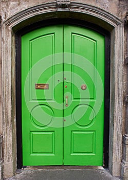 View of brightly colored traditional English green house door. Entrance door