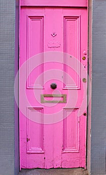 View of brightly colored traditional English pink house door. Entrance door