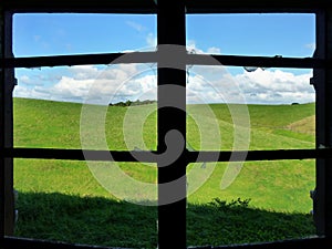 View through a broken window onto meadows