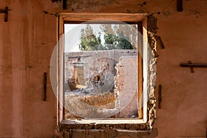 View through a broken window of ruined buildings and courtyard in Al Jazirah Al Hamra, UAE