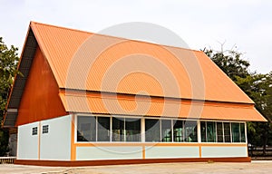 View of the building, shed, large hall with construction orange zinc roof covering transparent glass windows