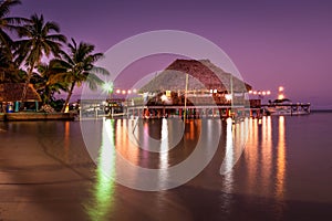 A view of the bungalow overwater beautifully lit up at dusk in Belize