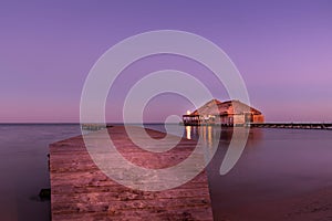 A view of the bungalow overwater beautifully lit up at dusk in Belize