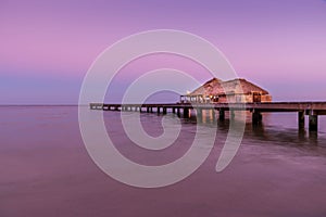 A view of the bungalow overwater beautifully lit up at dusk in Belize