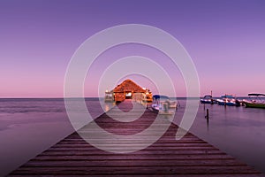 A view of the bungalow overwater beautifully lit up at dusk in Belize