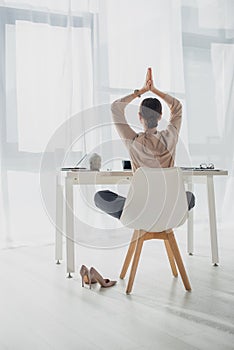 View of businesswoman meditating with namaste gesture at workplace with incense stick