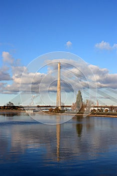 View of the cable bridge over the river Daugava. Riga, Latvia. Reflection of a cable-stayed bridge in the water against a cloudy