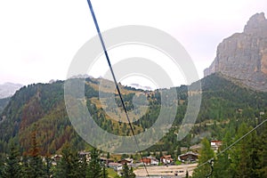 View from the cable car cabin to the village in the mountains and the Dolomites in Italy. Selective focus