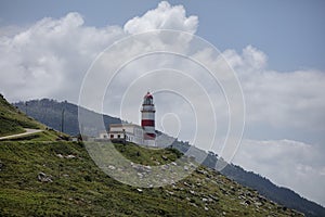 View of Cabo Silleiro lighthouse on a hill in Galicia, Spain under a cloudy sky photo