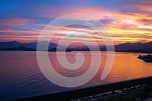 The view of the calm seascape in the shore under the colorful sunset.