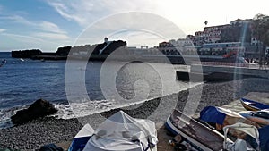 View Camara do Lobos bay and harbour, a small touristic fisherman\'s village, main avenue, boats and buildings,