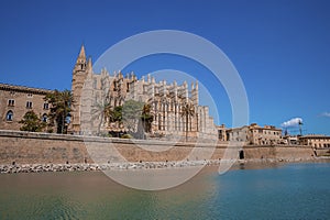 View of canal and gothic style La Seu Cathedral against clear blue sky