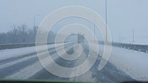 The view from the car driving on the highway through the snow drifts blizzard.