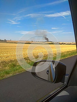 View from the car. Fire in field after wheat harvest in summer. Large explosion