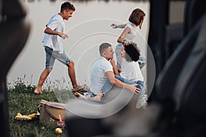 View From Car Happy Four Members Caucasian Family Having Picnic Outdoors by the Lake, Man and Woman with Two Teenage