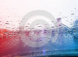 view from car on raindrops on window and road with police lights and silhouettes of cars driving behind him in rainy morning