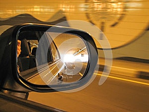 View in car rear mirror at tunnel in the evening