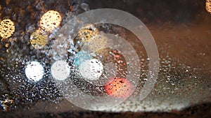 View from the car to the lights of the night city. Car with heated windshield. The car is in a traffic jam, snow falls on the glas