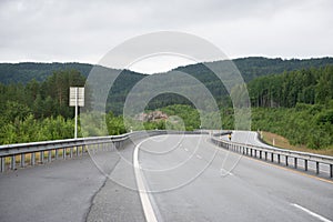 View from the car window of the Highway in the Norwegian mountains. Green coniferous trees on the hills