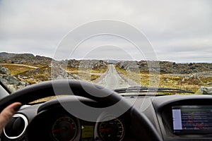 View from car window on the road and pity strange landscape with a mountains, rocks and cloudy sky and hand of woman. Landscape