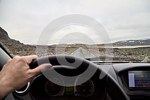 View from car window on the road and pity strange landscape with a mountains, rocks and cloudy sky and hand of woman. Landscape