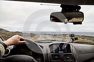 View from car window on the road and pity strange landscape with a mountains, rocks and cloudy sky and hand of woman. Landscape