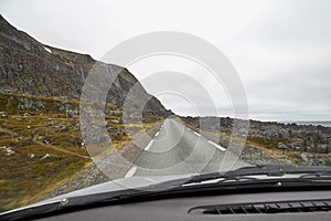 View from car window on the road and pity strange landscape with a mountains, rocks and cloudy sky. Landscape through windscreen