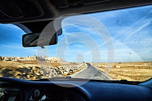 View from car window on the road and strange landscape with a valley, mountains and blue sky with clouds. Landscape through