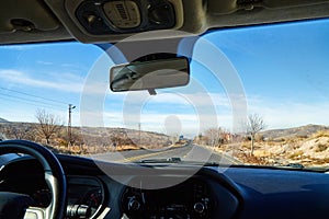 View from car window on the road and strange landscape with a valley, mountains and blue sky with clouds. Landscape through