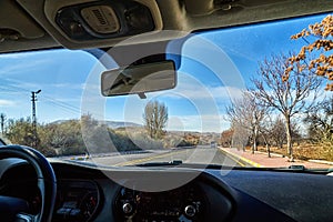 View from car window on the road and strange landscape with a valley, mountains and blue sky with clouds. Landscape through