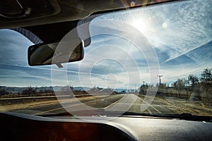 View from car window on the road and strange landscape with a valley, mountains and blue sky with clouds. Landscape through