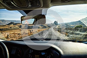 View from car window on the road and strange landscape with a valley, mountains and blue sky with clouds. Landscape through