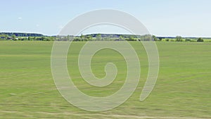 View from the car window to the side of the road and fields on a summer or spring day.