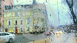 View car window,windscreen, windshield on rain water drops falling on glass city street,moving cars,at autumn cloudy day