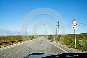 View from car windscreen with stripe relief to highway, tundra and blue sky in norht region at a sunny day