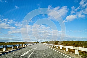 View from car windscreen with stripe relief to highway, tundra and blue sky in norht region at a sunny day